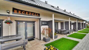 A reception area with a sign reading "RECEPTCJA," outdoor seating, and a well-maintained lawn.