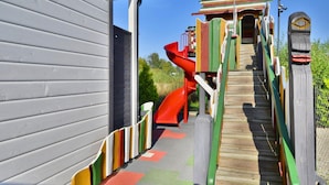 A playground with a wooden slide and a colorful play structure. - Holiday Homes Near the Sea, Sauna, Whirlpool (Ustronie Morskie)
