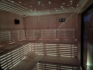 A sauna with wooden benches and a ceiling with embedded lights. - Holiday Homes Near the Sea, Sauna, Whirlpool (Ustronie Morskie)