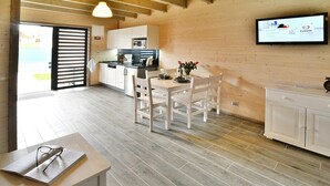 A modern kitchen with white cabinets, a dining table with chairs, and a television mounted on the wall. - Holiday Homes Near the Sea, Sauna, Whirlpool (Ustronie Morskie)