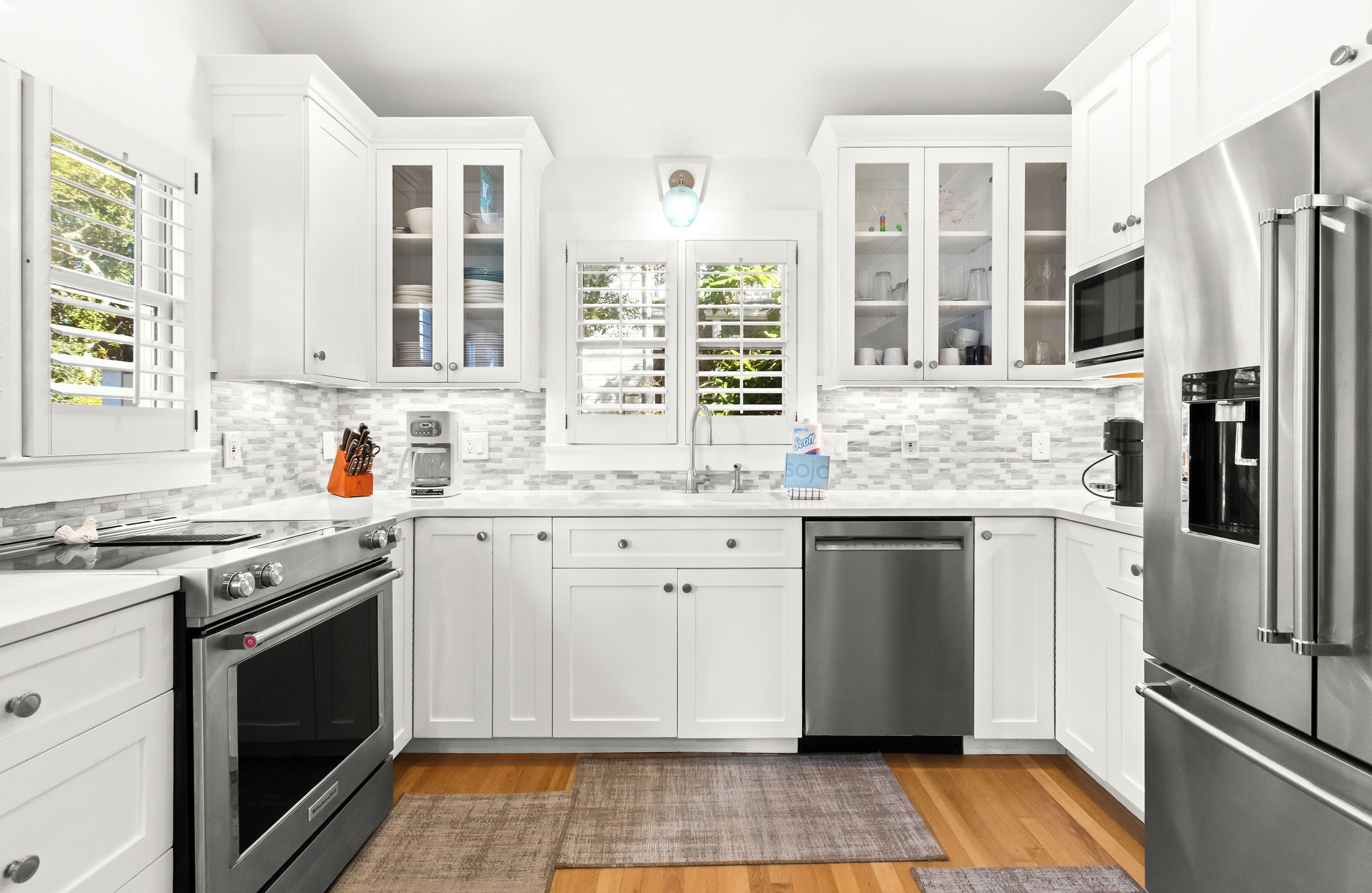 Una cocina moderna con armarios blancos, electrodomésticos de acero inoxidable y un salpicadero de azulejos.