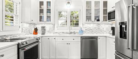 Una cocina moderna con armarios blancos, electrodomésticos de acero inoxidable y un salpicadero de azulejos.