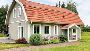 Une maison à deux étages, avec un toit recouvert de tuiles rouges, un porche abrité et une pelouse bien entretenue.