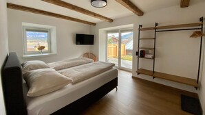 Un dormitorio con cama, televisor, ventana con vista y techo de madera.