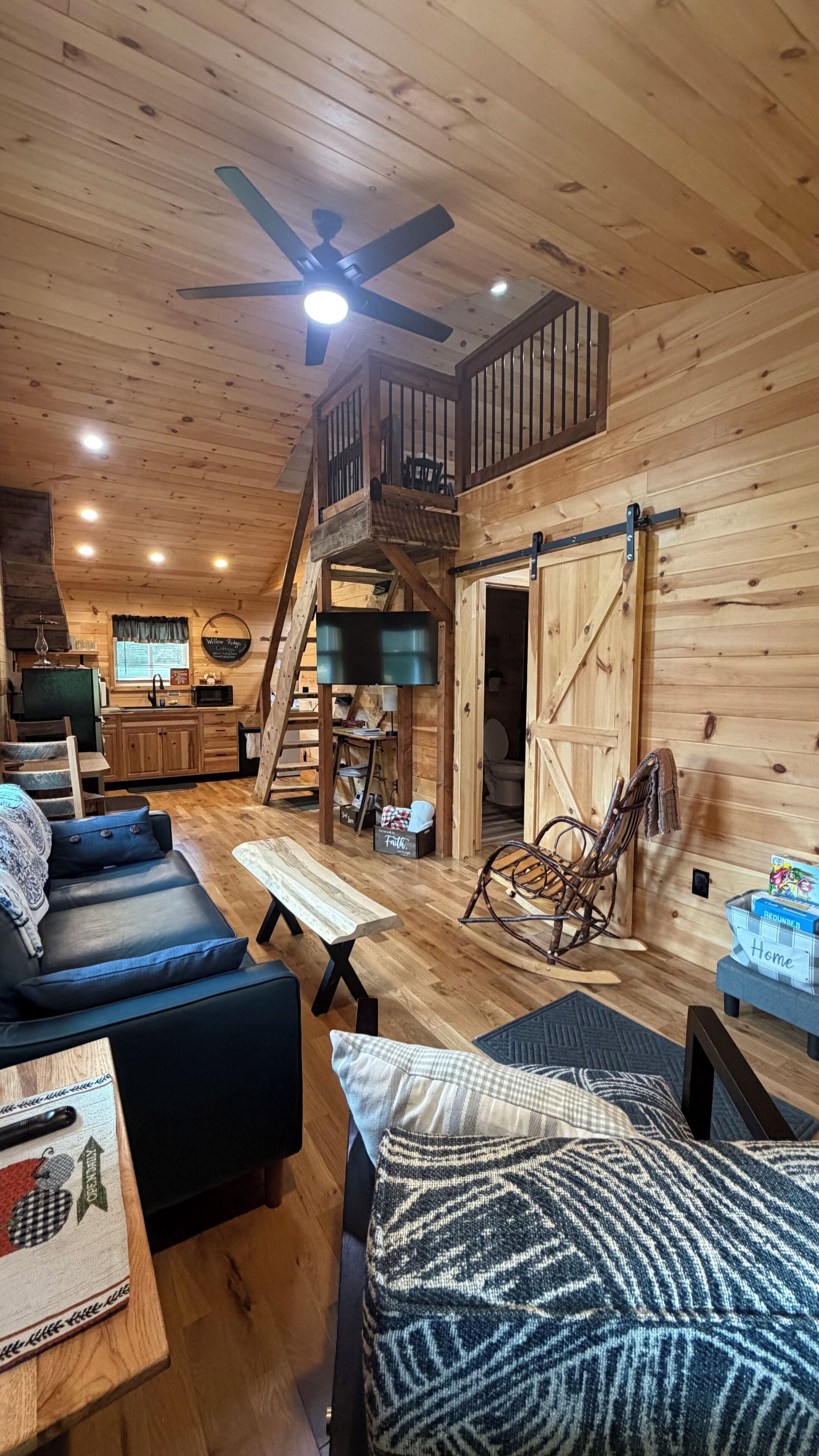 A wooden interior with a loft bedroom, a dining area, and a kitchen.