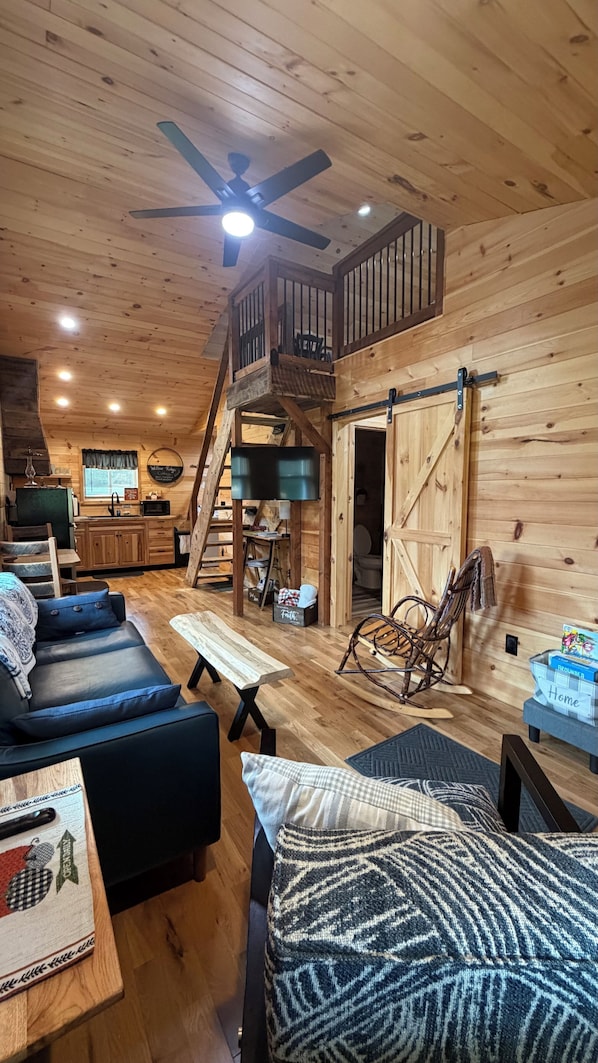 A wooden interior with a loft bedroom, a dining area, and a kitchen.