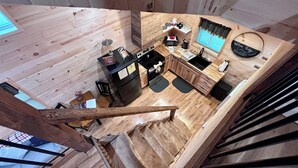 A cozy cabin-style room with a wooden interior, a kitchenette, and a small seating area.