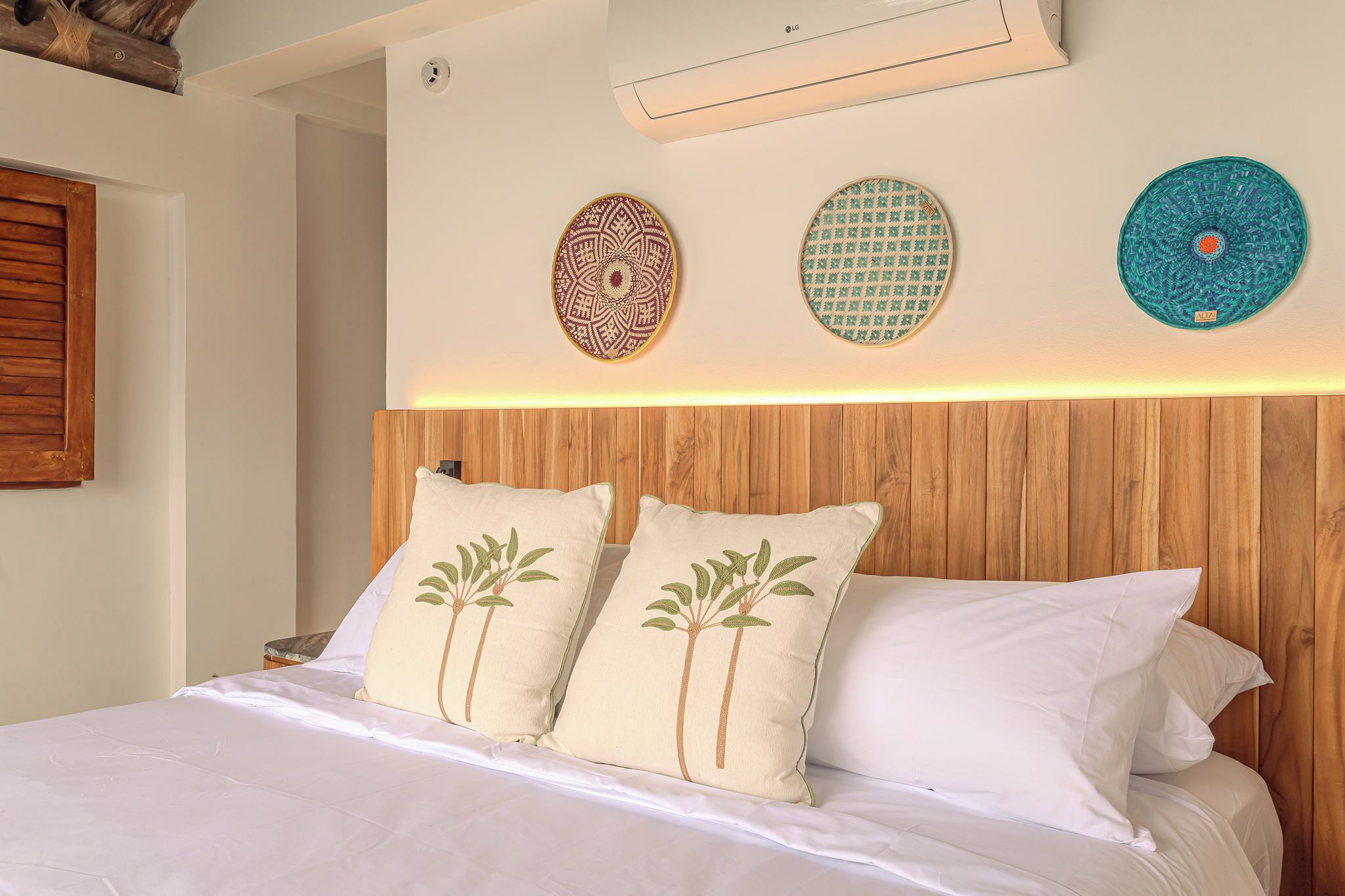 A bedroom with a wooden headboard, a bed with white bedding, and decorative wall art.