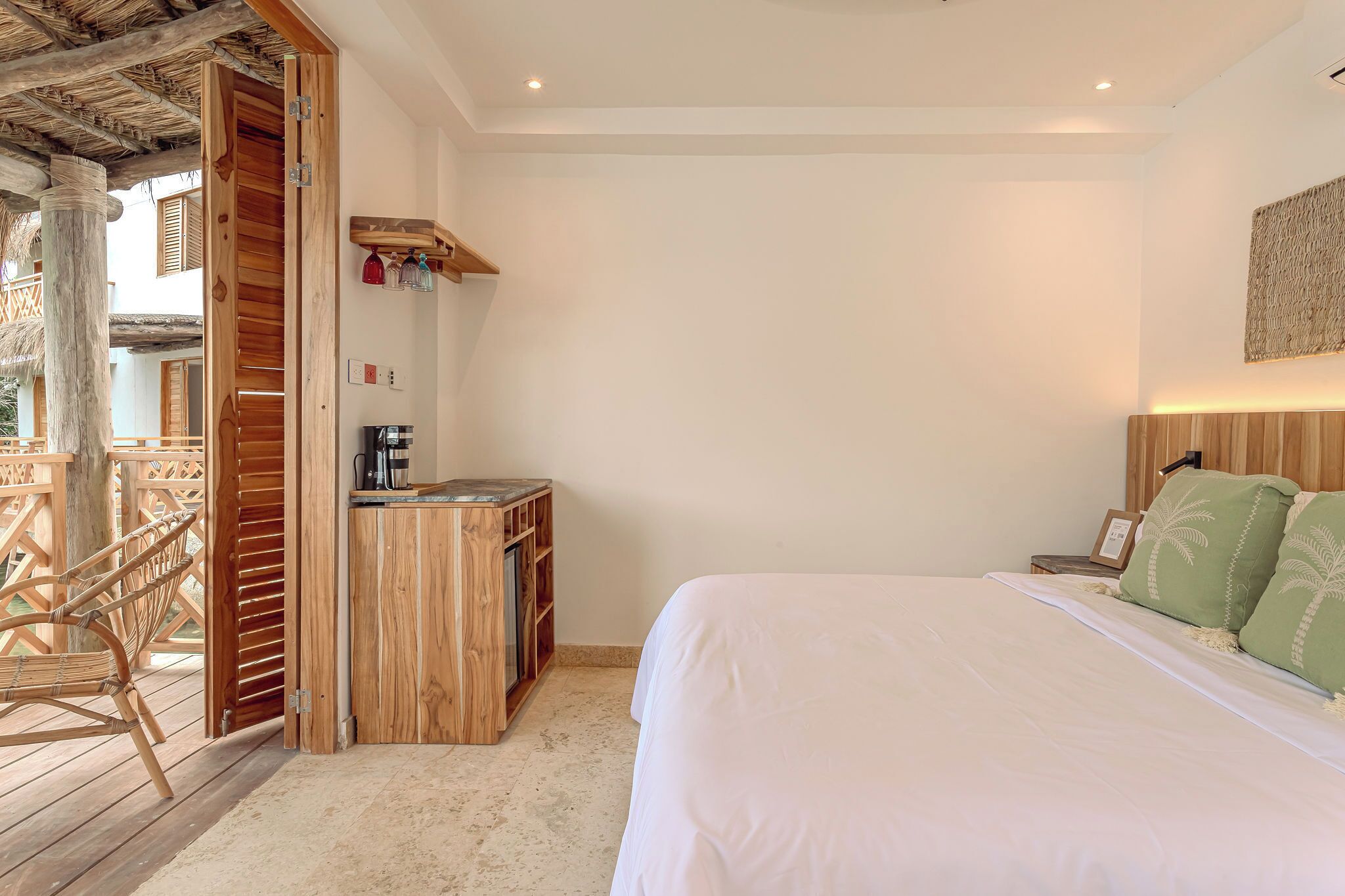 A bedroom with a bed, a wooden desk, a chair, and a balcony.