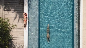 A rectangular swimming pool with clear water, surrounded by a wooden deck and a concrete edge.