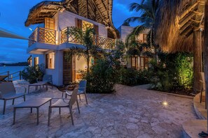 A beachfront property with a thatched-roof structure, outdoor seating, and lush greenery. - Soy Local Islawa (Cartagena)