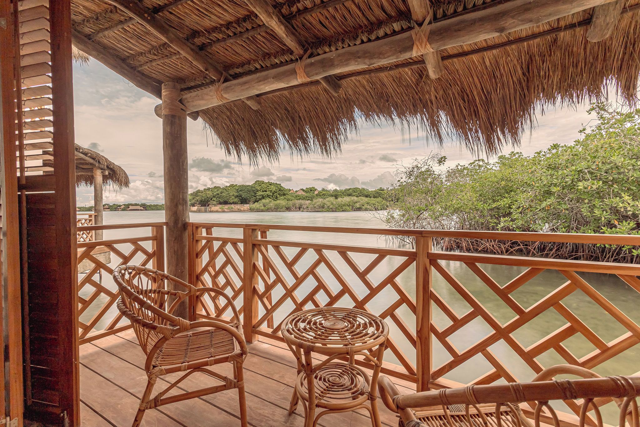 A wooden deck with wicker furniture overlooking a river, surrounded by a wooden fence.