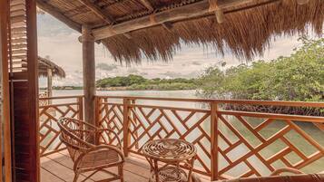A wooden deck with wicker furniture overlooking a river, surrounded by a wooden fence.