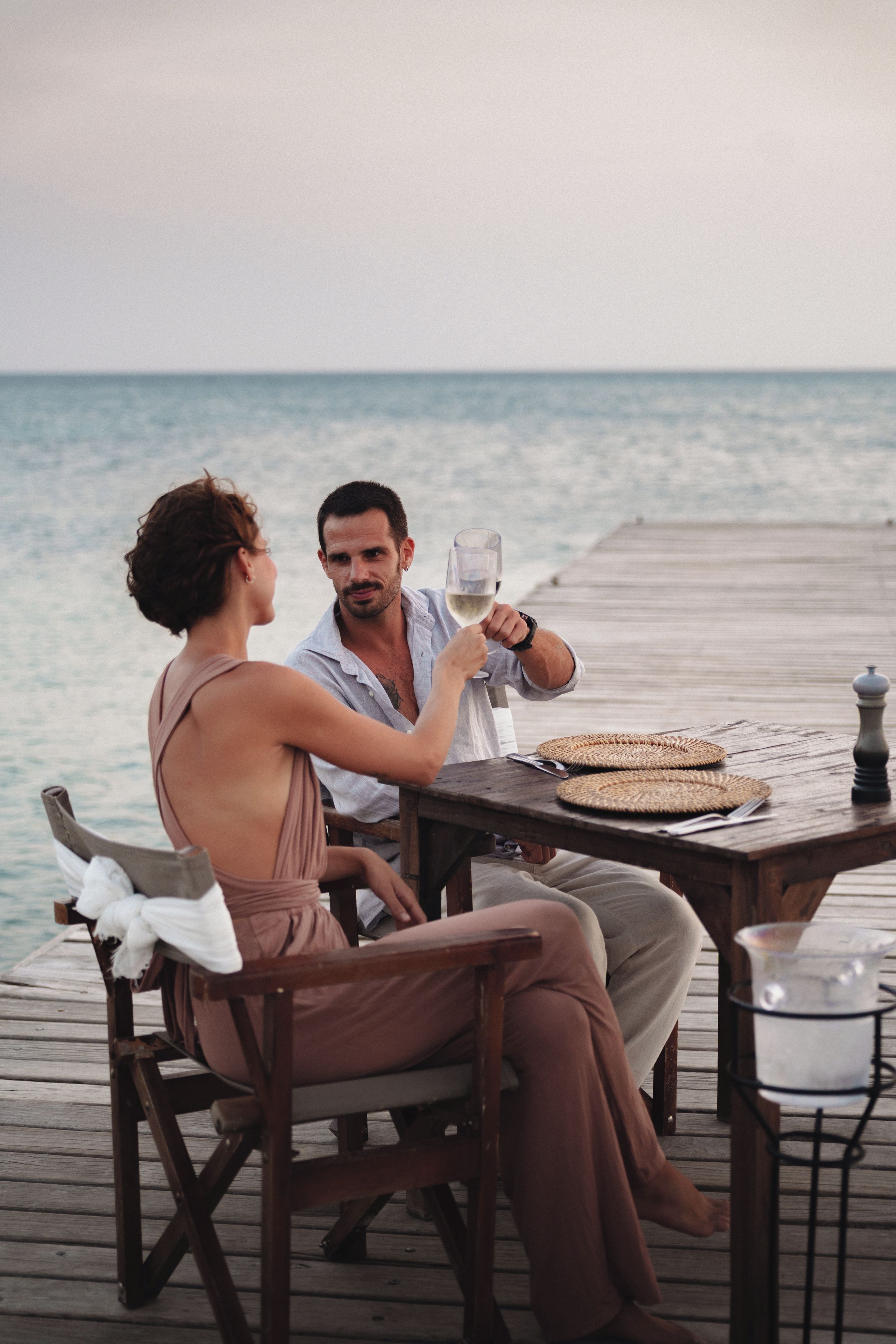 A couple dining on a wooden deck with a view of the sea.
