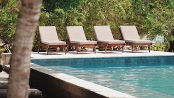 A poolside area with lounge chairs and a clear blue pool.