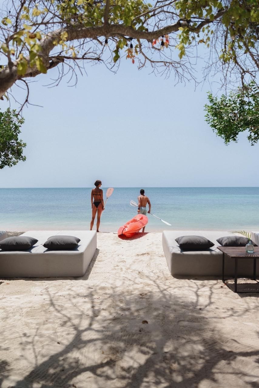 A beach with lounge chairs and a kayaker.