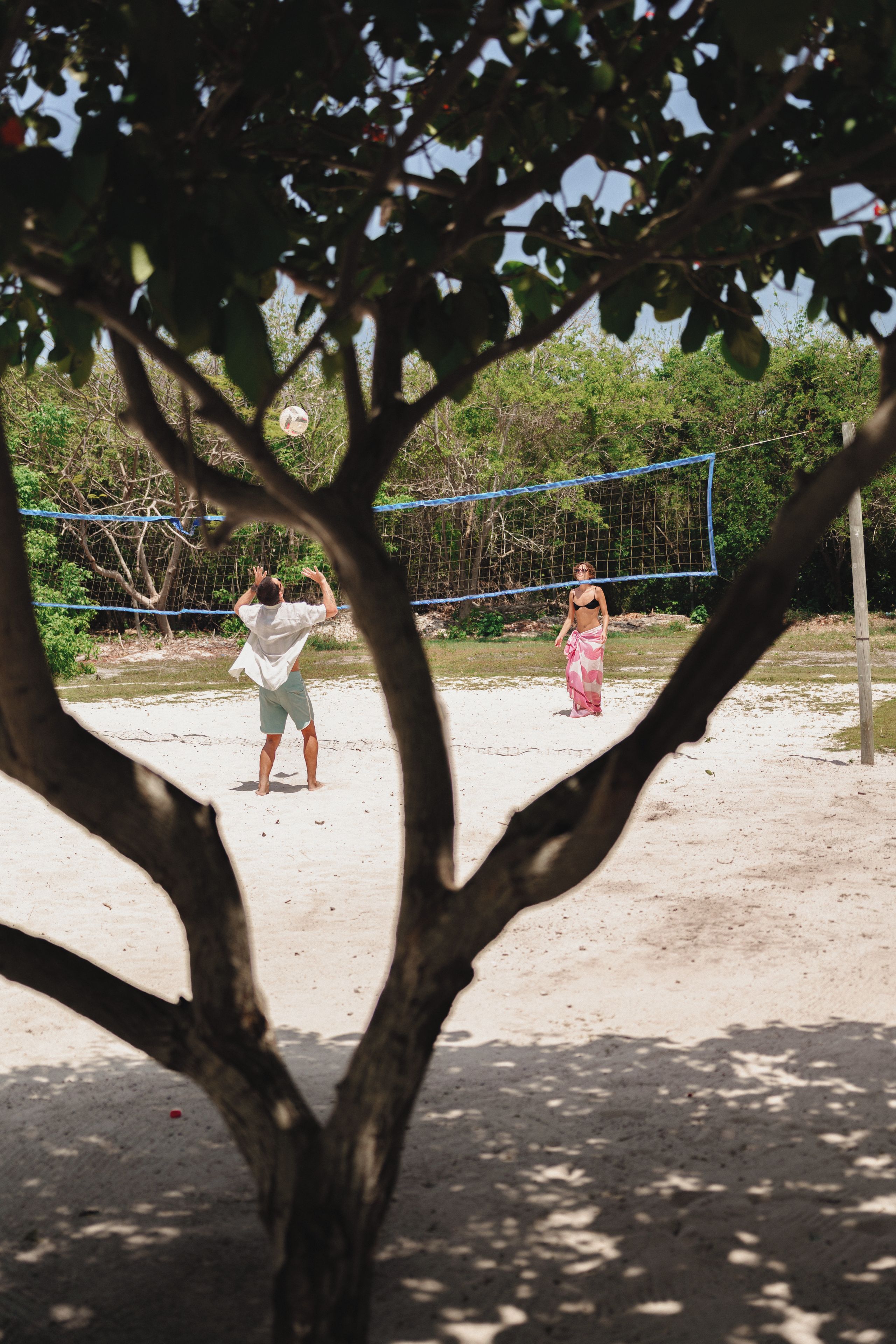 Una red de voleibol con dos jugadores al fondo.