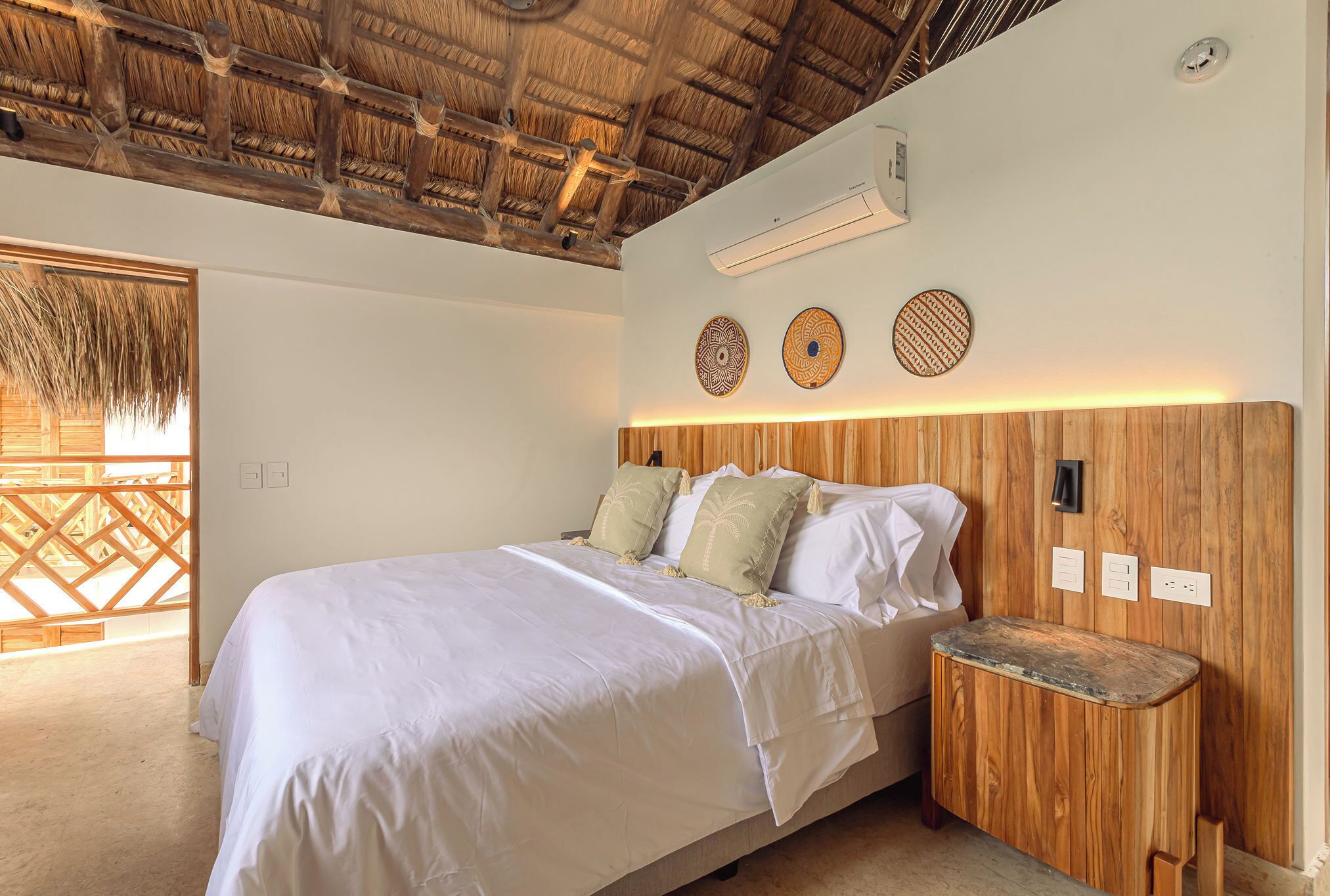 Quarto com cama, cabeceira de madeira e mesa de cabeceira.