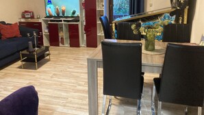 Una sala de estar moderna con televisor, un comedor con sillas, una zona de cocina y un espejo decorativo.