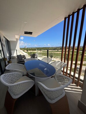 Un área de comedor al aire libre, moderna, con una mesa de vidrio y sillas de mimbre, con vistas a un paisaje pintoresco.