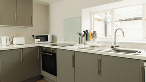 Una cocina moderna con armarios grises, un microondas, un fregadero y una ventana que proporciona luz natural.