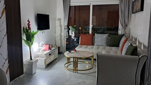 Un salón moderno con un sofá, una mesa de centro redonda y un televisor montado en la pared.