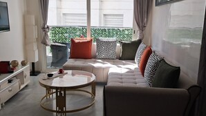 Una sala de estar moderna con un sofá, una mesa de centro redonda de vidrio y un televisor montado en la pared.