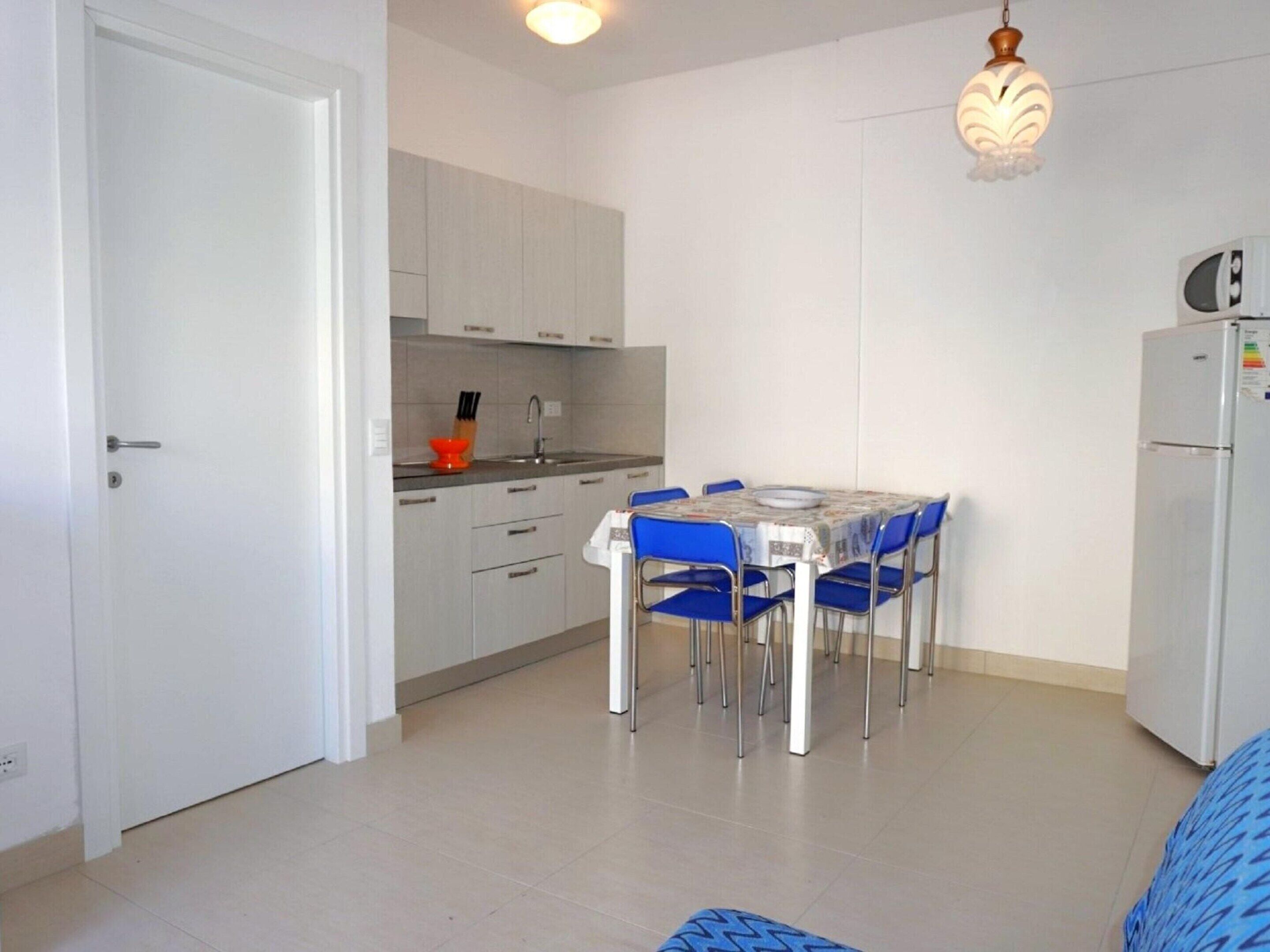 A compact kitchen with a dining table, chairs, and a refrigerator.