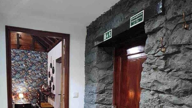 A hallway with a stone wall, a wooden door, and a bench. - Casa Monte de Paz 1

 (Calheta)