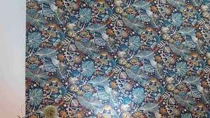 A room with a wooden ceiling, a patterned wallpaper, a bedside table with a lamp, and a bed with a patterned bedspread. - Casa Monte de Paz 1

 (Calheta)