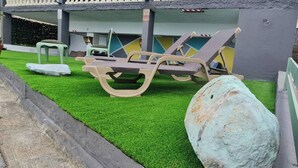 A pool area with lounge chairs and a large rock. - Casa Monte de Paz 1

 (Calheta)