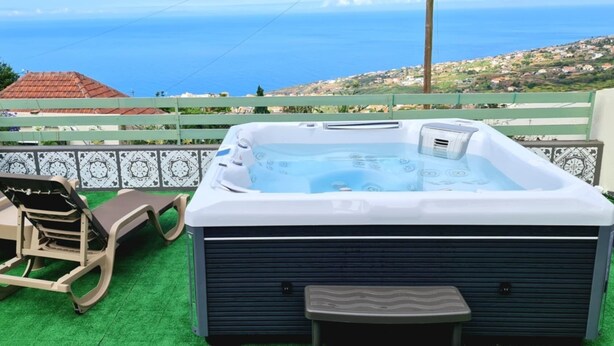 Un bain à remous doté d’un panneau de commande, de deux chaises longues et offrant une vue sur la mer.
