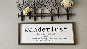 A framed sign with the word 'wanderlust' and its definition.