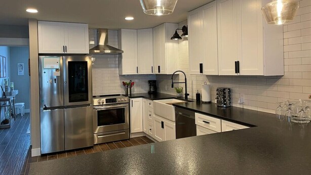 A modern kitchen with white cabinets, stainless steel appliances, and a black countertop.