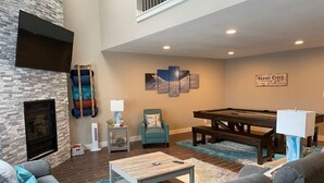 A spacious living room with a fireplace, a pool table, and a comfortable seating area.