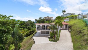 A large, multi-story building with a red-tiled roof, surrounded by lush greenery and a clear sky. - Nice Pool w Breathtaking Mountain Views BBQ (Carolina)
