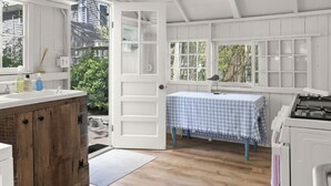 A kitchen with wooden cabinets, a white ceiling fan, and a window with a view of greenery. - Close Walk to Bustling Main Street and Steps Away from a Beautiful Beach (Harwich)