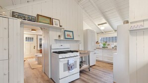 A kitchen with white cabinetry, a stove, and a refrigerator. - Close Walk to Bustling Main Street and Steps Away from a Beautiful Beach (Harwich)
