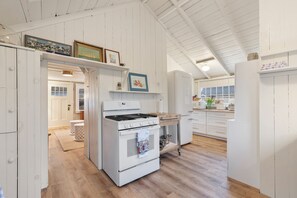 A kitchen with white cabinetry, a stove, and a refrigerator.