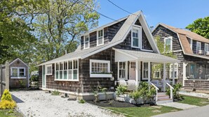 A two-story house with a sloped roof, a covered porch, and a small front yard with plants. - Close Walk to Bustling Main Street and Steps Away from a Beautiful Beach (Harwich)