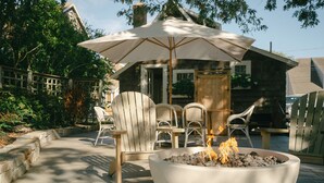 A patio area with a fire pit, outdoor furniture, and a wooden fence. - Close Walk to Bustling Main Street and Steps Away from a Beautiful Beach (Harwich)