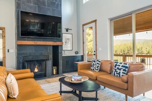 A living room with a fireplace, a sofa set, a coffee table, and a large window with a view.