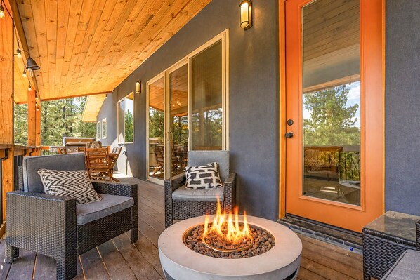 A covered patio with wicker furniture, a fire pit, and a glass door leading to an outdoor area.
