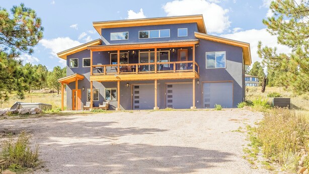 Une maison moderne à deux étages, dotée d’un porche abrité, de grandes fenêtres et d’un garage.