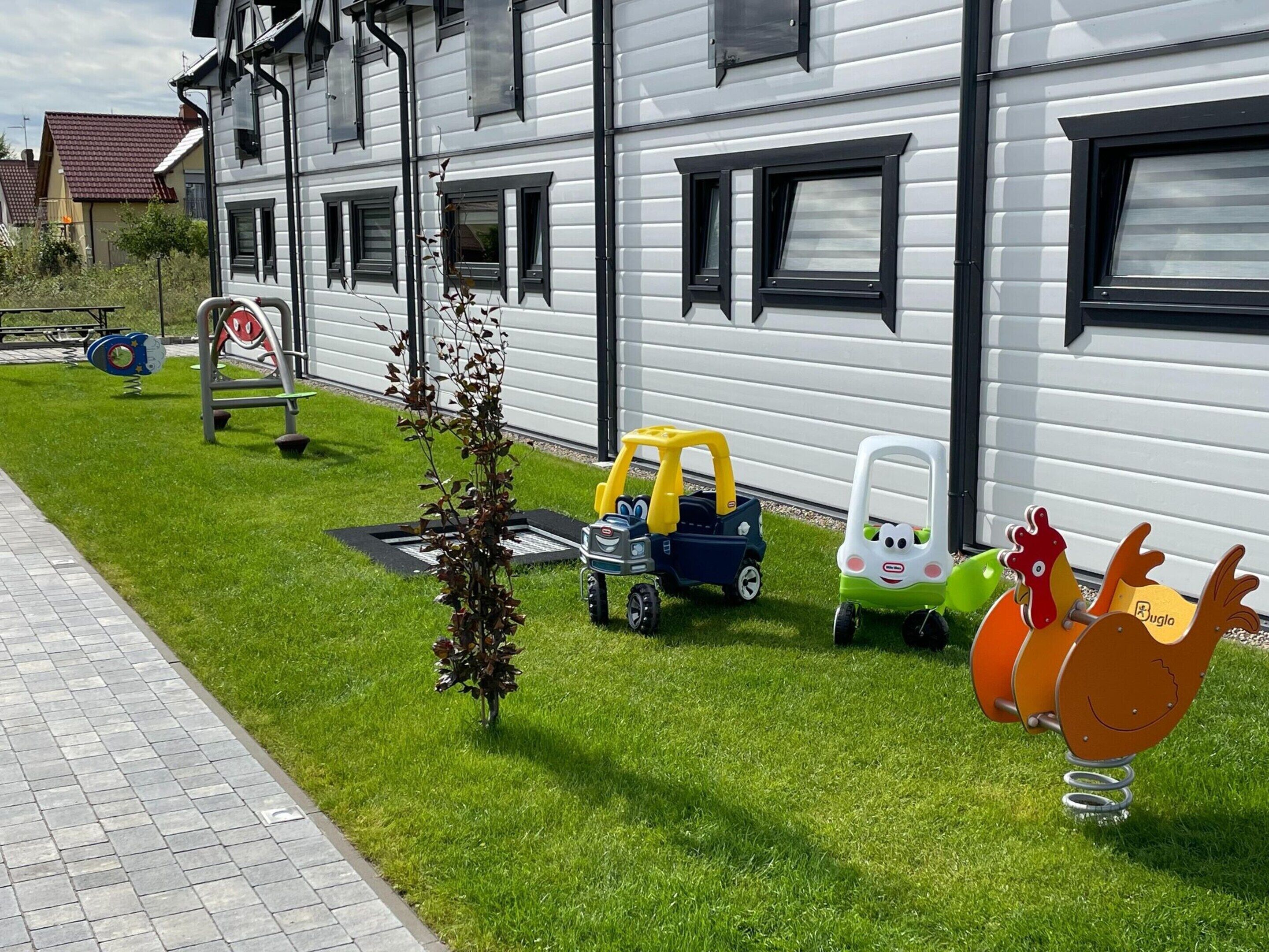Een woongebouw met een verzorgd gazon, buitenspeeltoestellen en een kleine tuin.