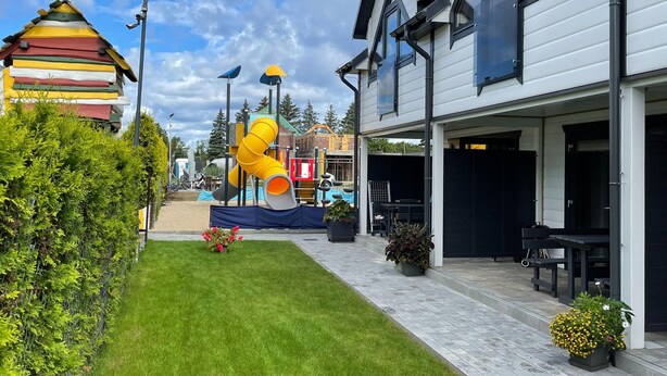 Ein Wohngebiet mit einem modernen Haus, einem Spielplatz und einem gepflegten Rasen.