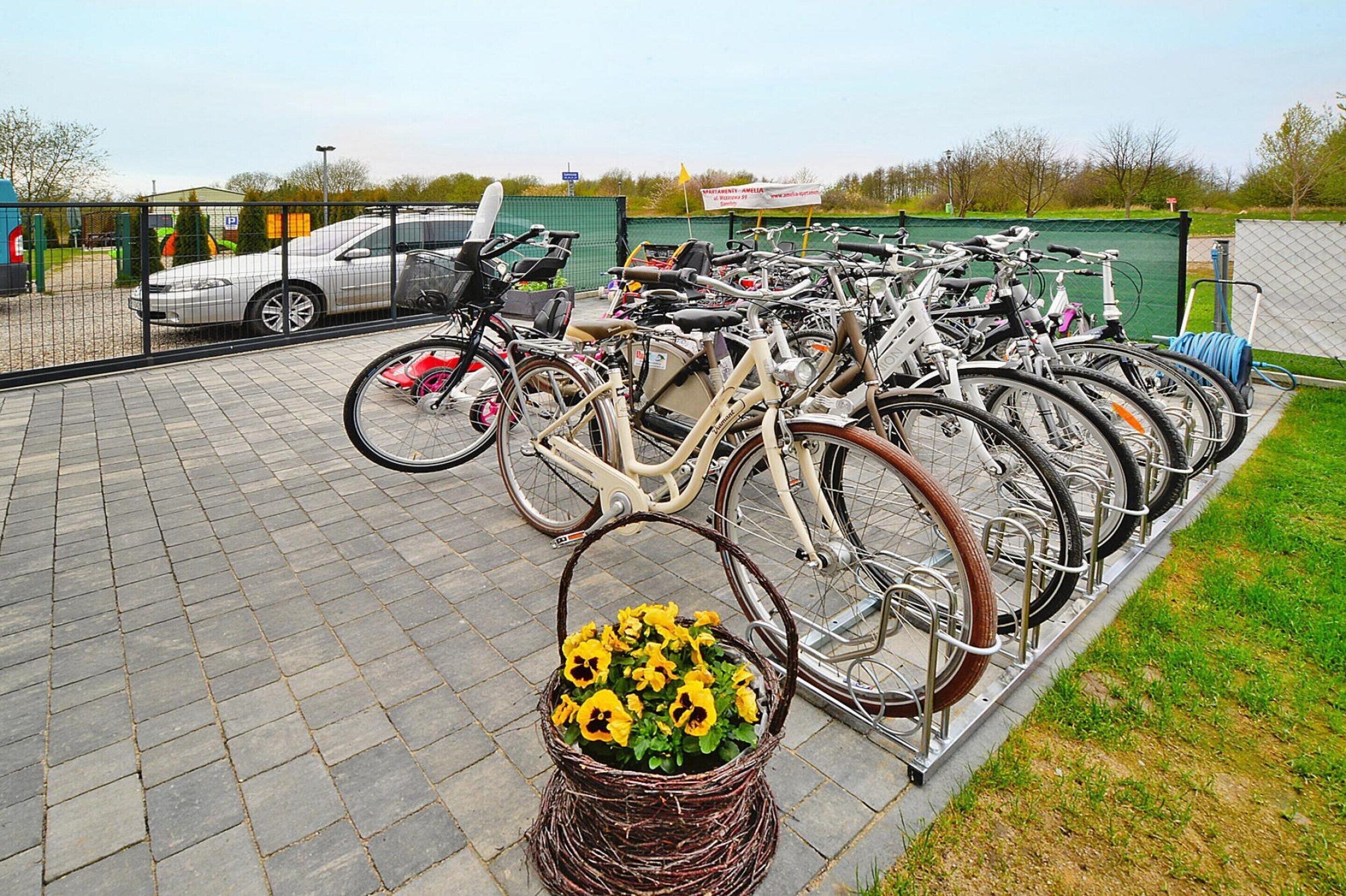 Un espace de stationnement pour vélos agrémenté d’un panier de fleurs.
