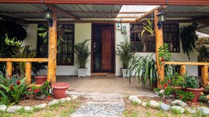 Une maison avec une véranda en bois, des plantes en pot et un porche carrelé.