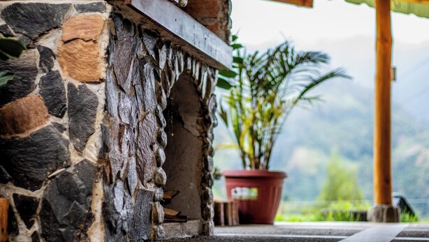 Un mur de pierres avec une poutre en bois et une plante en pot en arrière-plan.