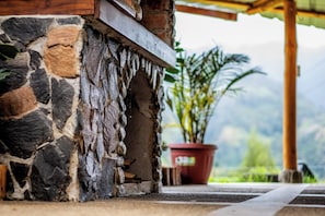 Un muro de piedra con una viga de madera y una planta en maceta al fondo.